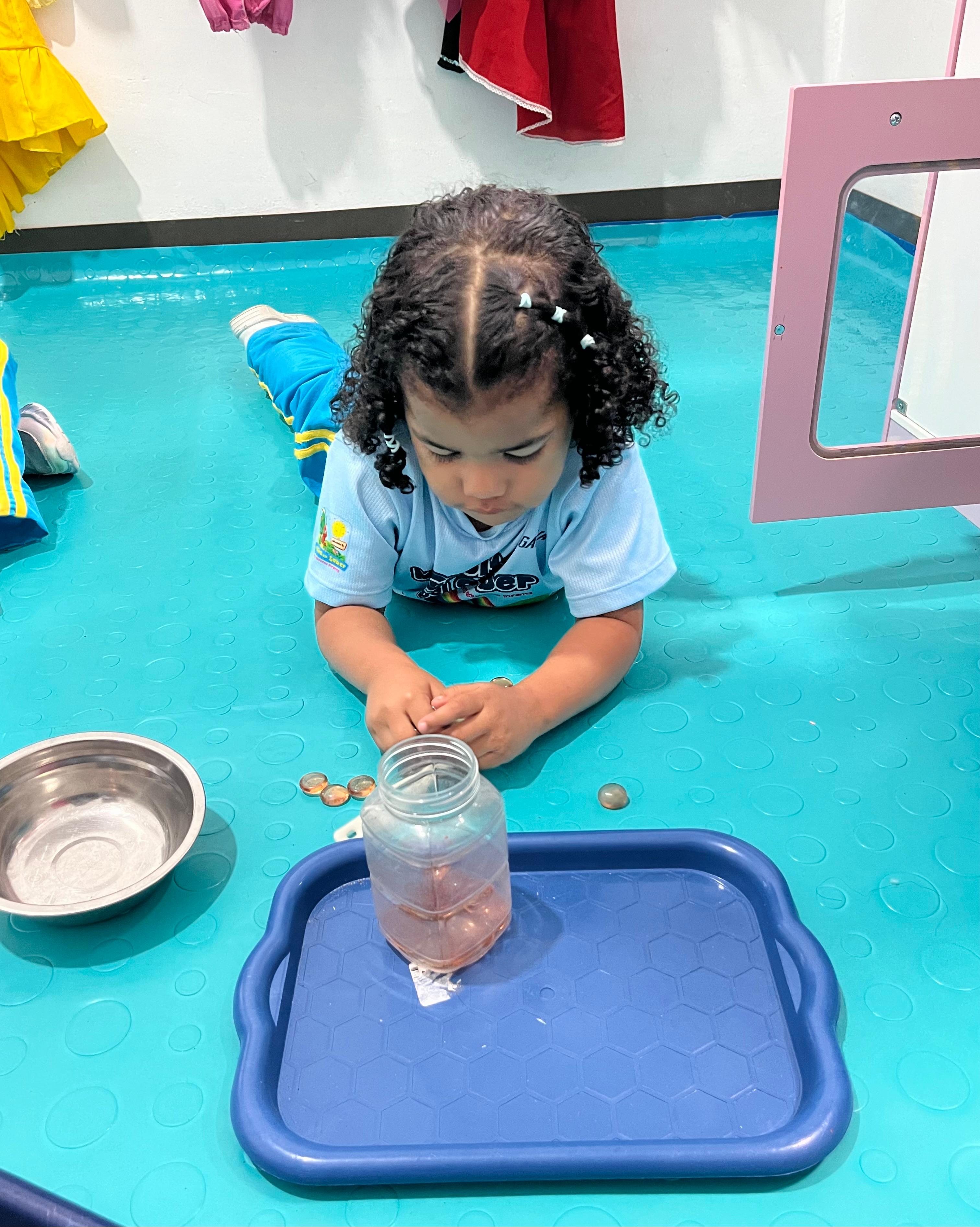 Niña practicando motricidad fina con bandeja Montessori