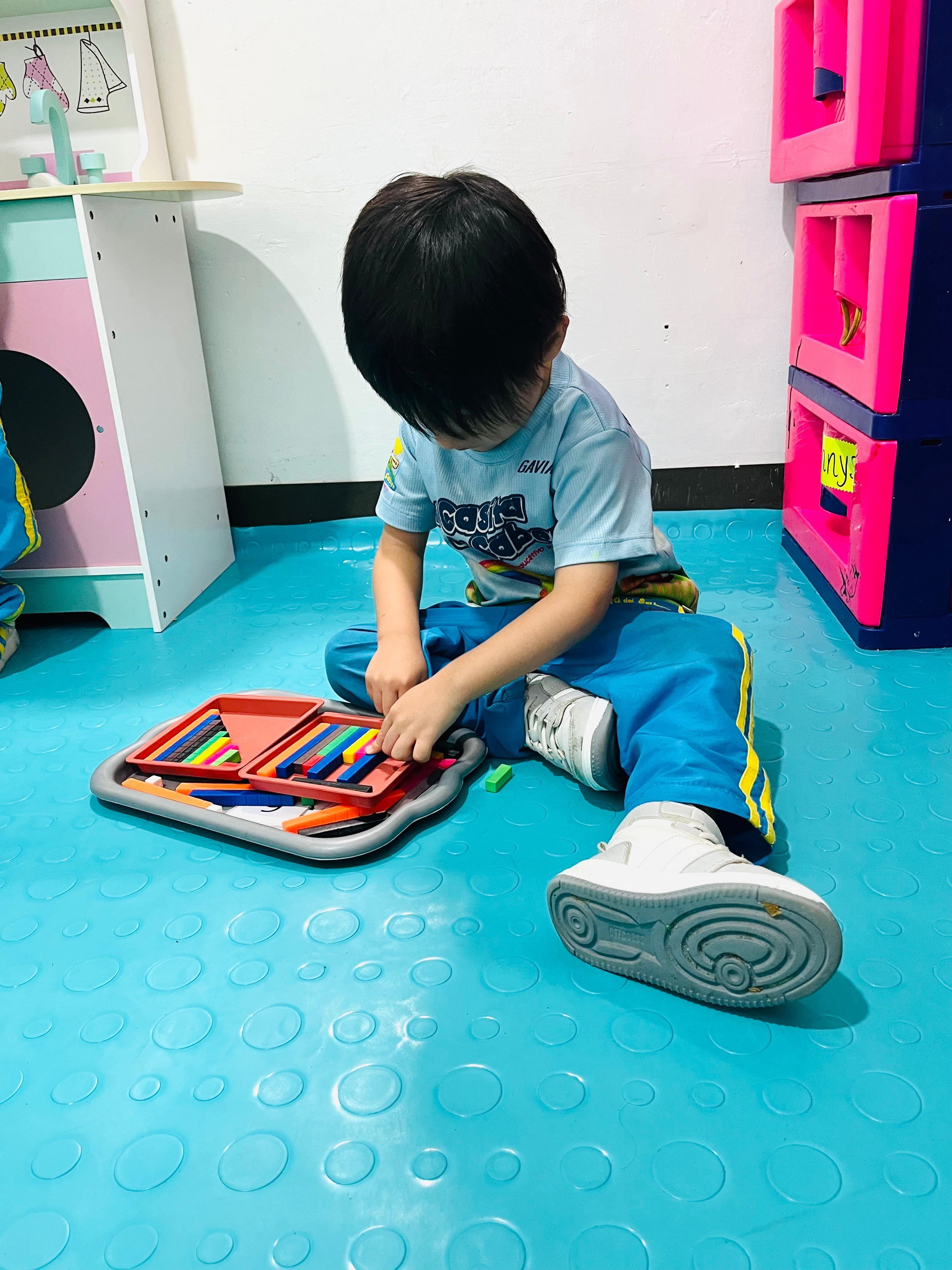 Niño clasificando colores en bandeja Montessori